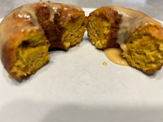 Pumpkin donuts on a white plate covered in maple glaze.